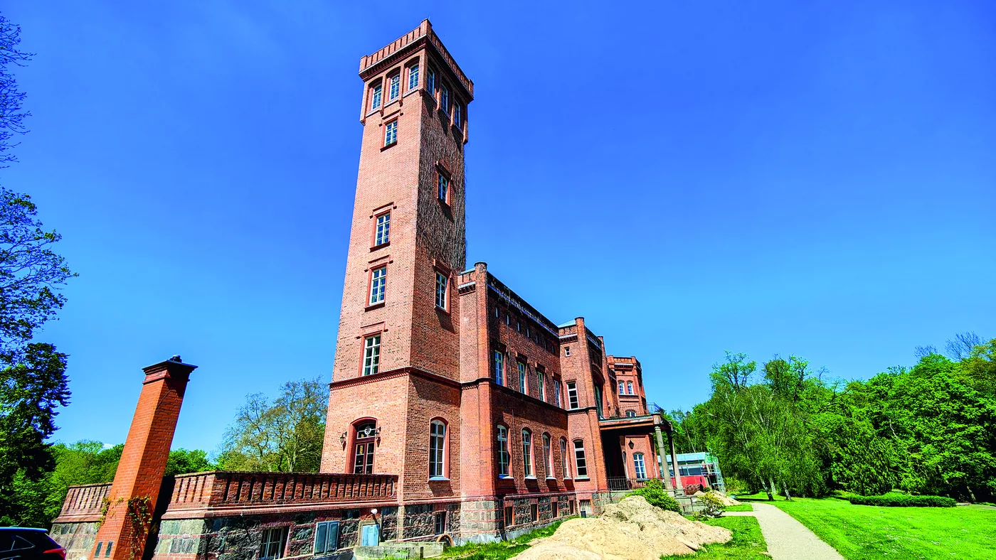 Hoher Backsteinturm eines historischen Gebäudes vor blauem Himmel
