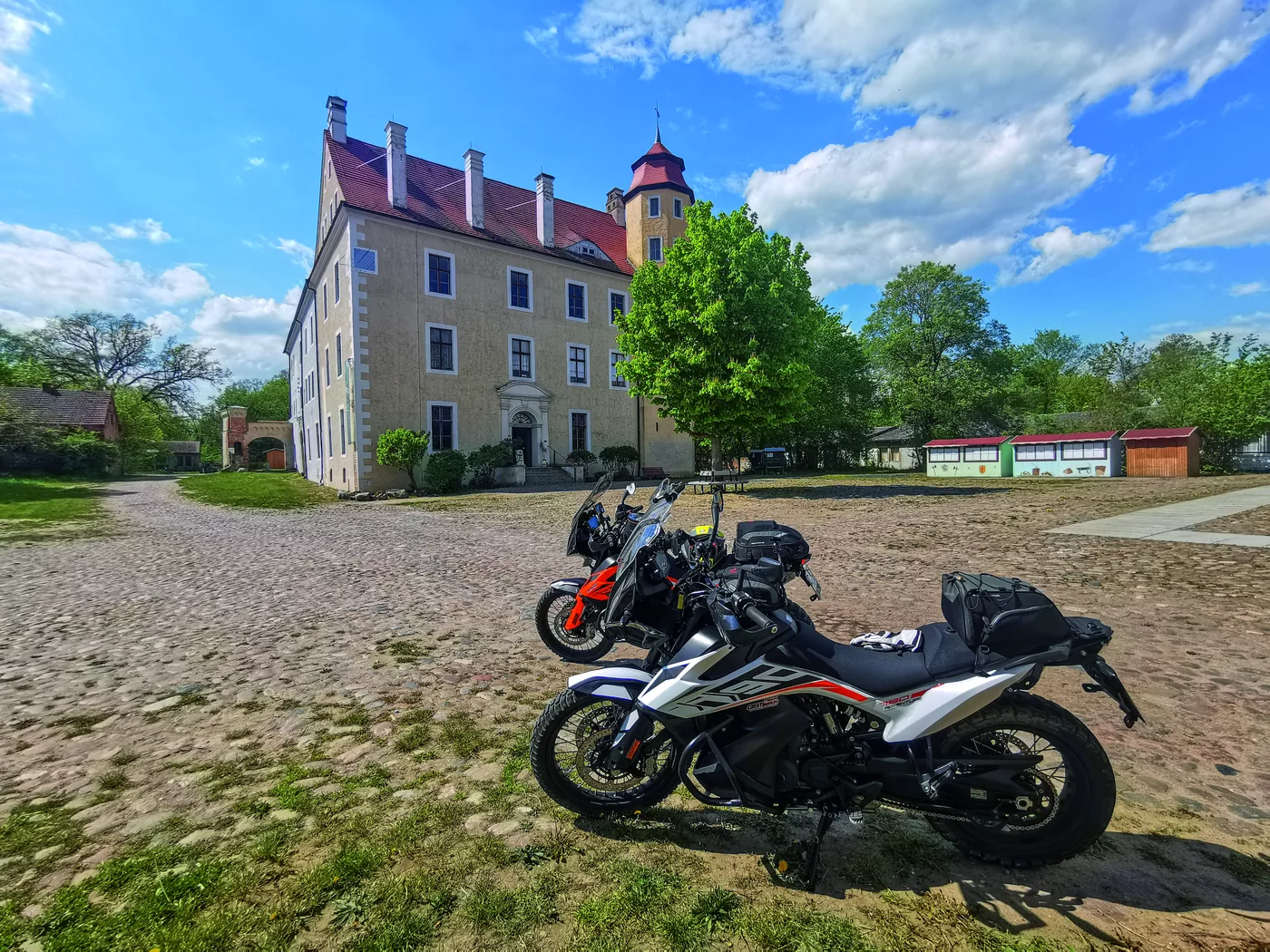 Motorrad vor einem alten Gutshaus mit Ecktürmchen